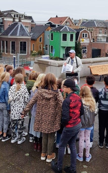 Een klas luistert naar een gids op de brug in Zaandam